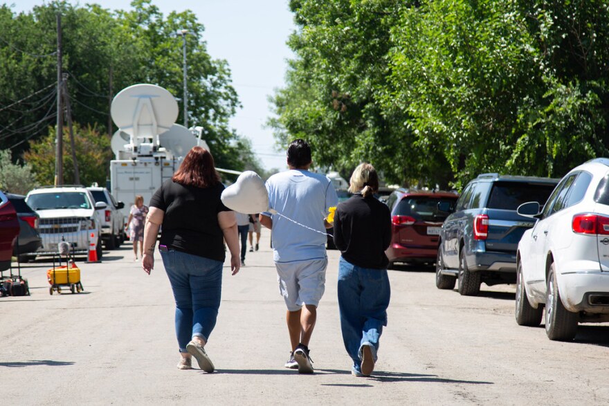  Community members carrying a heart-shaped balloon walk toward a memorial at Robb Elementary School in Uvalde on Thursday. 