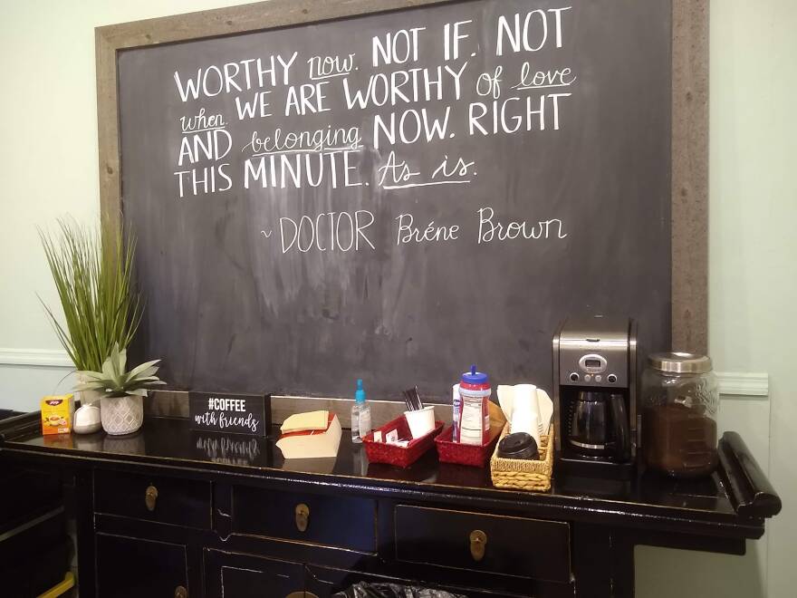 "A sign holds a quote from Brene Brown - Worth now. Not if. Not When. We are worthy of love and belonging now. Right this minute. As is."