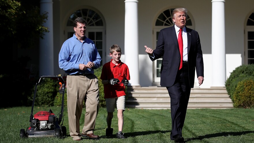 Eleven-year-old Frank "FX" Giaccio walks with President Donald Trump while mowing the grass in the Rose Garden of the White House on Friday. Also pictured is Frank's father, Greg Giaccio.