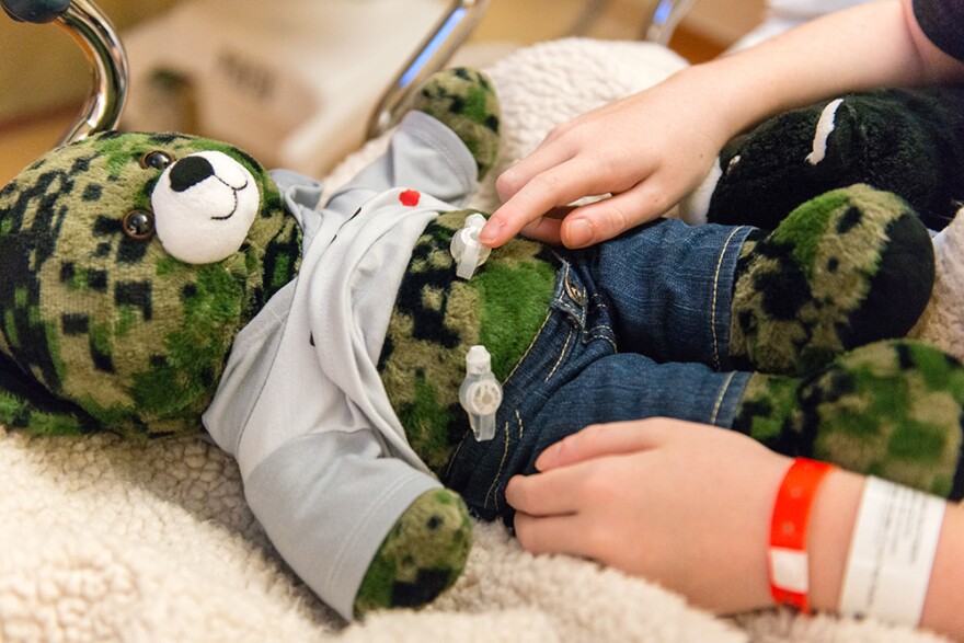 Matthew Husby points to a gastrostomy tube on his teddy bear that is similar to the one surgeons inserted in his own stomach. Role-playing helps kids relax, doctors say.