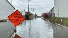 A flooded street with a "road closed" sign