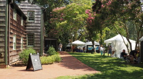 Image displaying tents of artists' work under the wooded canopy at Rehoboth Art League's wooded campus.