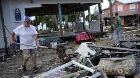 Employee Lisa Bell dumps out a shovel full of mud as business owners and employees start cleaning up at the storm-damaged business The Marina, in Horseshoe Beach, Fla., Thursday, Aug. 31, 2023, one day after the passage of Hurricane Idalia.