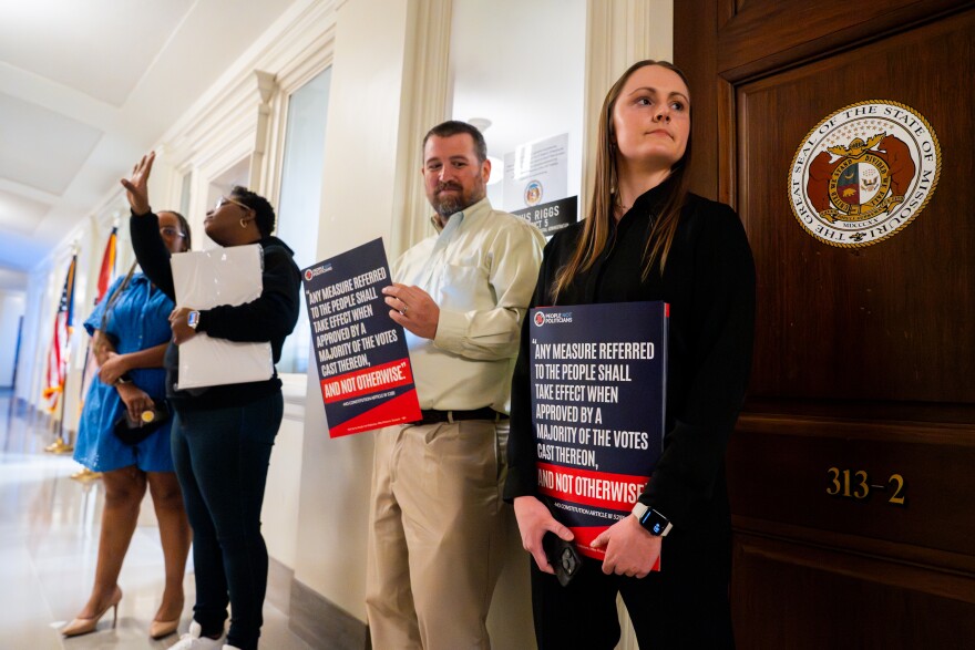 People Not Politician Deputy Director Emily Gerber and Executive Director Richard von Glahn hold signs decrying the attempt to gerrymander Missouri's congressional map to favor Republicans on Jan. 13 at the state Capitol in Jefferson City.