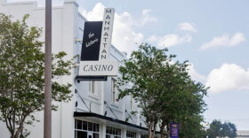 White building with black and white sign reading the historic Manhattan Casino with trees around it 