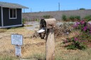 A burned-out mailbox is adorned with a kukui nut lei in front of an empty lot where a home once stood in Lahaina before the 2023 fires. (Aug. 4, 2025)