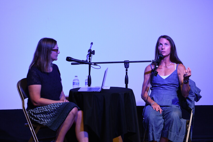 Erin interviews Melissa, seated by a black table with two microphones