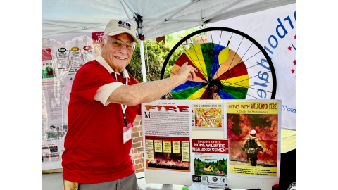 Ted Zislis of Age-Friendly Carbondale spins the Wheel of Fortune at the AFC wildfire preparedness booth during July’s First Friday. With a microgrant from AARP, Zislis wants to educate the community about wildfire resilience.