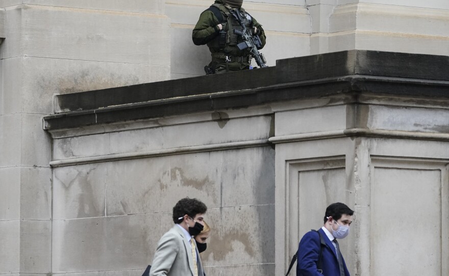 A member of the Georgia State Patrol SWAT team looks on as people walk by outside of the Georgia State Capitol after the opening day of the legislative session on Monday in Atlanta. State capitols across the country are under heightened security after the siege of the U.S. Capitol last week.