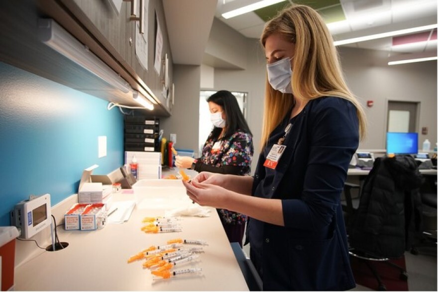 Nurses prepare the first dose of the Moderna COVID-19 vaccine at the OSF vaccination clinic in Peoria in this February 2021 file photo.