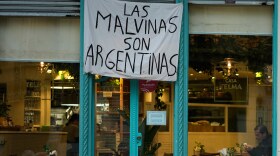 A man sits at a restaurant displaying a banner reading "The Malvinas are Argentine," referring to the Falkland Islands, also known as Malvinas, in Buenos Aires, Argentina, Monday, July 27, 2026.