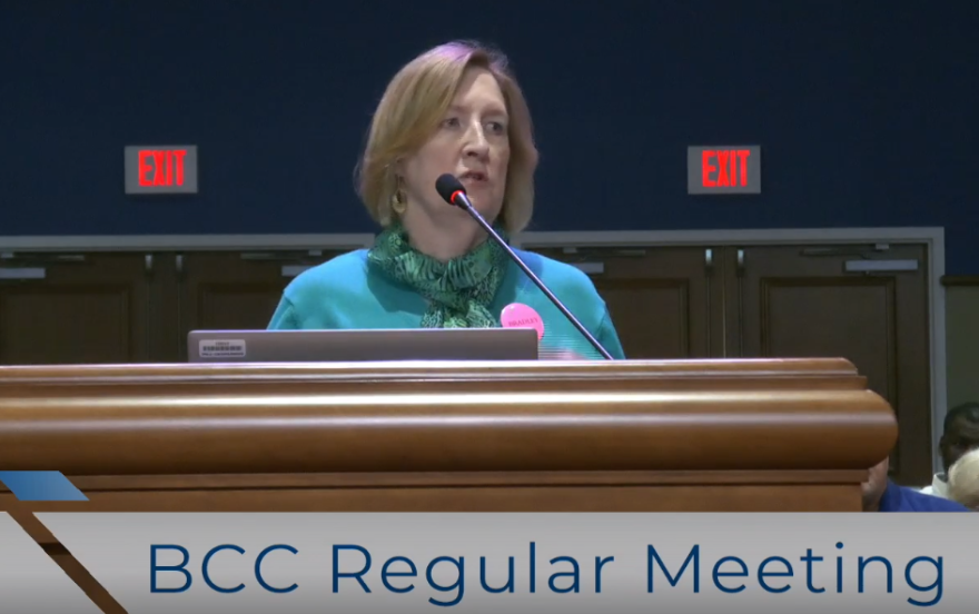 Retired West Florida Public Libraries librarian Cindy Burden speaks to the Escambia County Commission about the Library Director selection process. Burden wore a pink button reading “BRADLEY” in support of candidate Bradley Vinson during Thursday’s meeting.