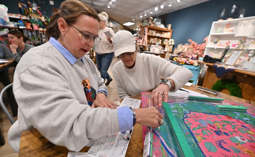 Kim Mecca assists Donna Carey with her hand in mah-jongg.