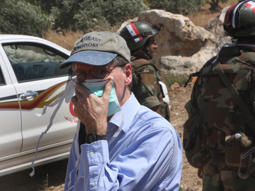In this photo taken during a government-organized tour for  foreign diplomats and the media, US ambassador to Syria Robert Ford covers his nose from the smell of the dead bodies during his visit with other foreign diplomats to a mass grave, in Jisr el-Shughour, north of Syria, on Monday, June 20, 2011.