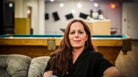 Jessica Hicklin sits on a couch with a pool table in the background.