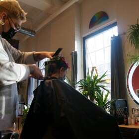 A hairstylist about to shave the back of a little boy's head.