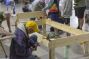 A man is kneeled down building a bed frame.