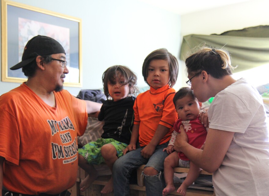 Galen Huntsman and Arianne Swihart with their three children, Tobie, Azriel, and Aurora, in the one-room apartment the family shares at Safe Harbor, a supportive housing facility for families transitioning out of homelessness. (Zachariah Hughes/Alaska Public Media, Anchorage)
